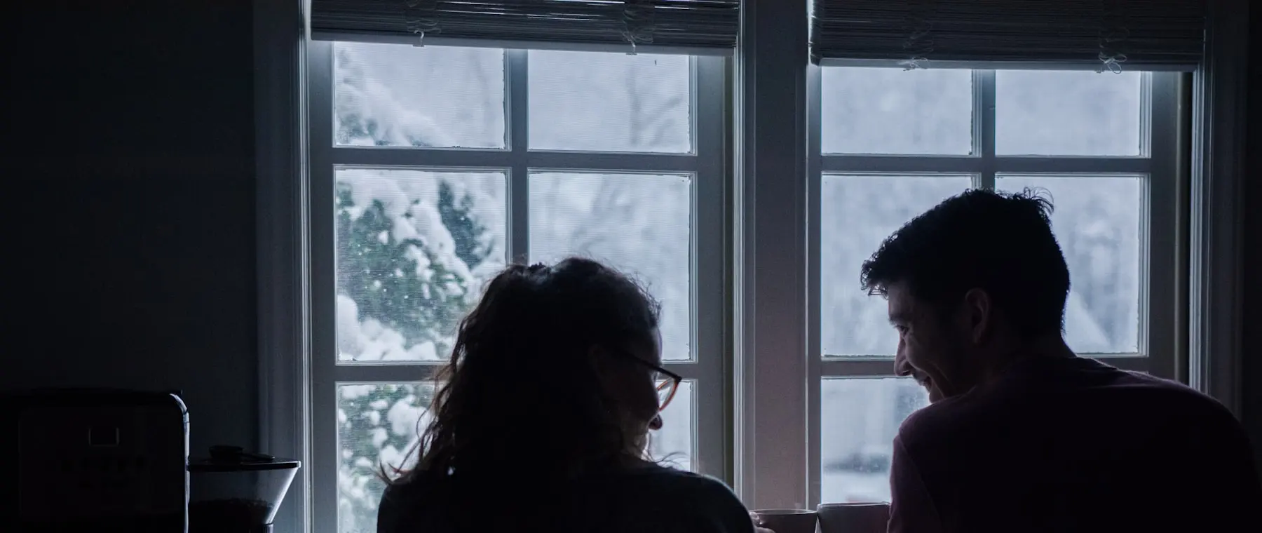 Two people talking beside a window